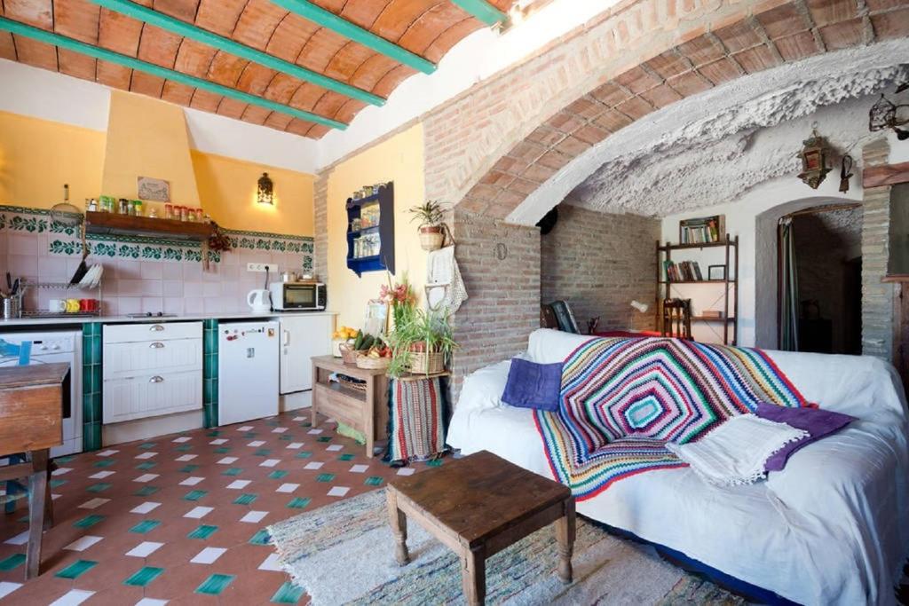 a living room with a white couch and a kitchen at La Constanza Casa Cueva in Granada