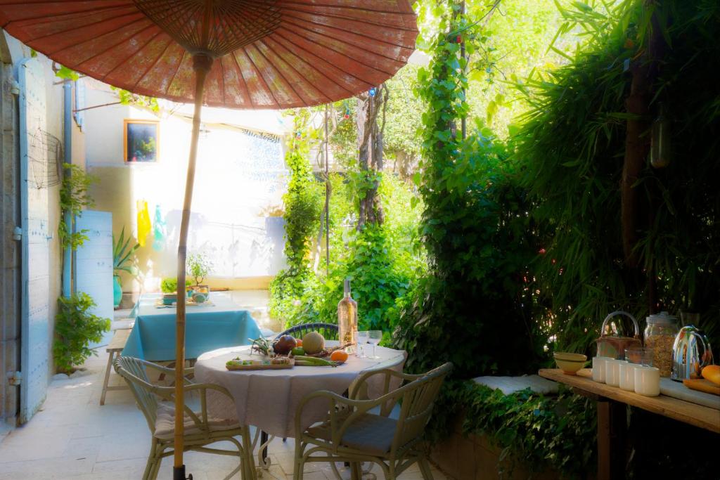 a table and chairs with an umbrella on a patio at Maison d'hôtes , ancien Hôtel des colonnes in Riez