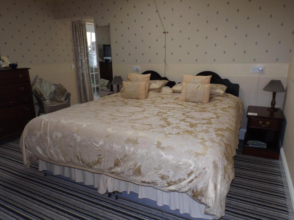a bedroom with a large bed with white sheets and pillows at Rosedene Guest House in Pembroke