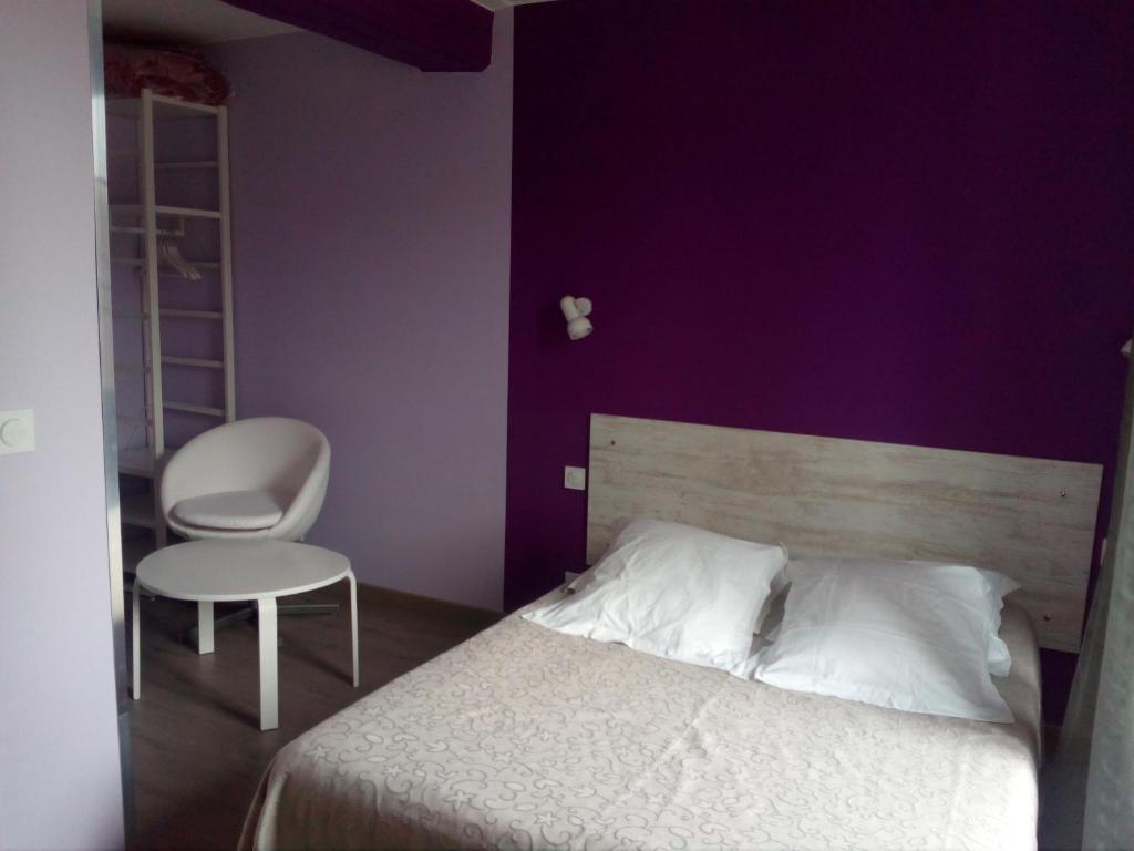 a bedroom with a bed and a chair and purple wall at Chambres d&#39;hôtes d&#39;Accolay in Accolay