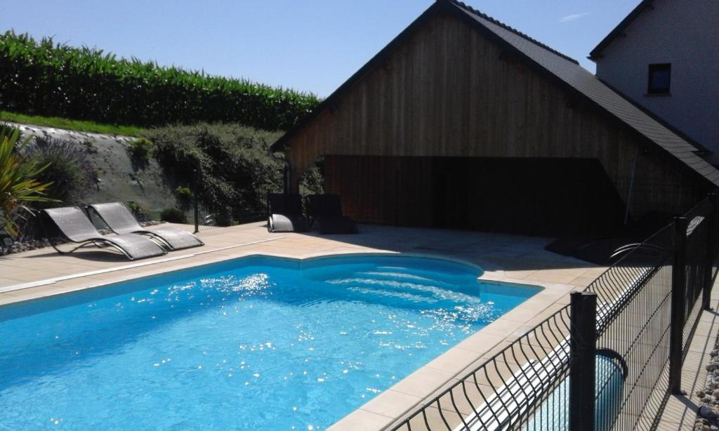 a swimming pool with two chairs and a fence at L'Escale Normande in Saint-Jean-des-Champs