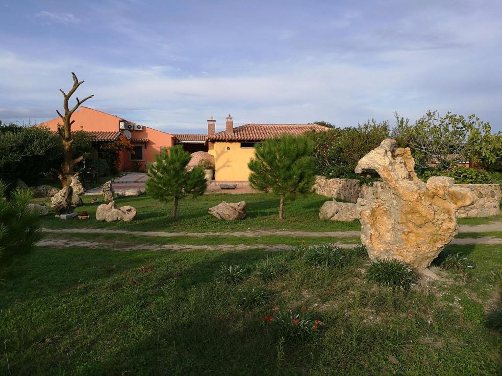 uma escultura de pedra num quintal com uma casa ao fundo em Country House Vignola Mare em Aglientu