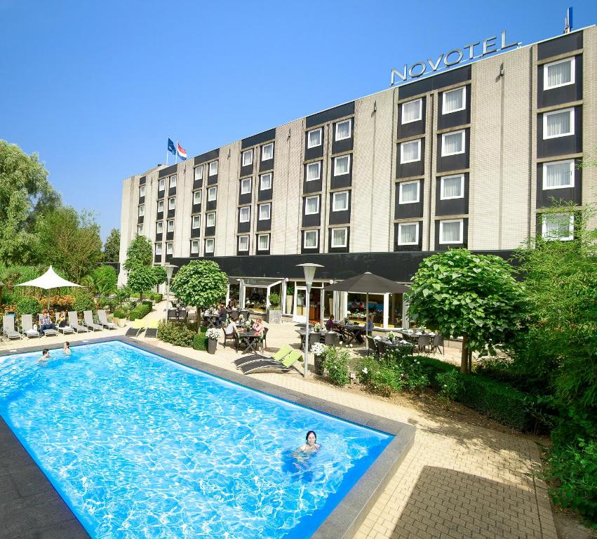 a large swimming pool in front of a large building at Novotel Maastricht in Maastricht