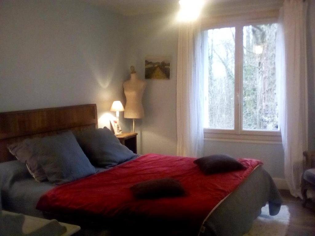 1 dormitorio con 1 cama con manta roja y ventana en La corniche, en Chaumont