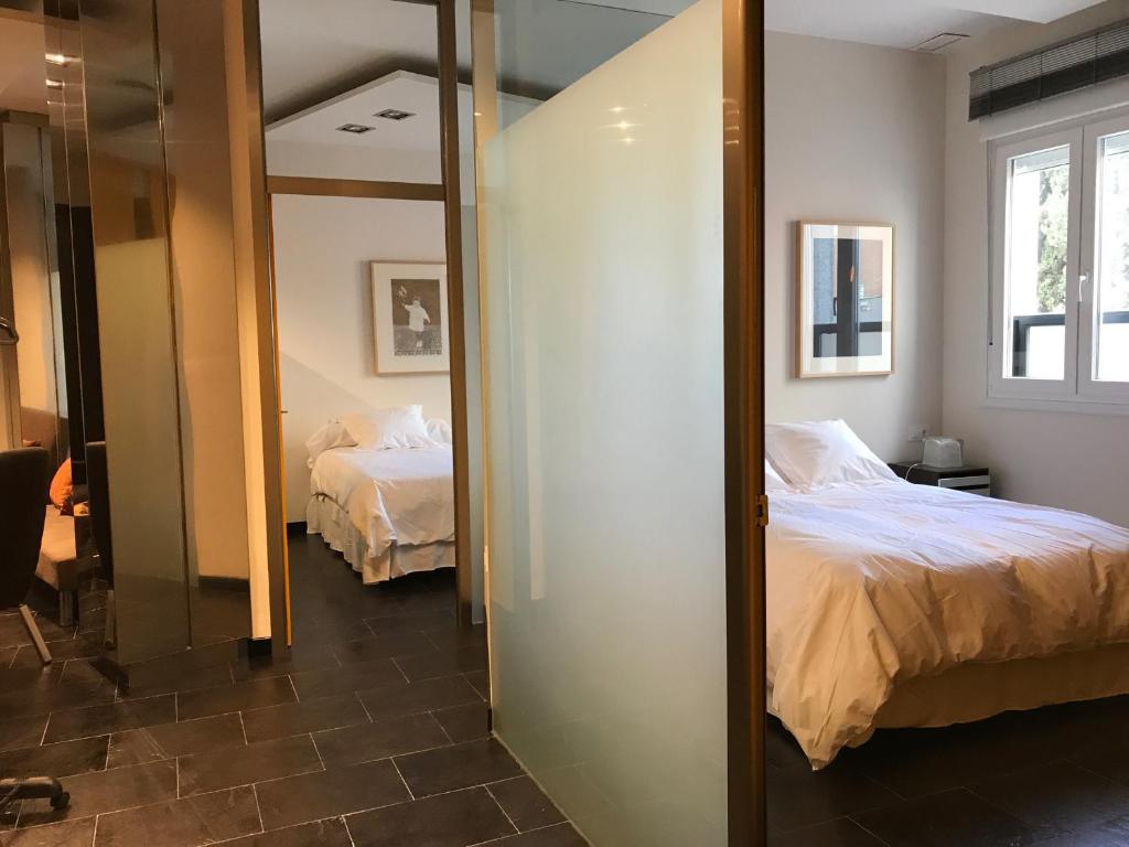 a bedroom with a mirror and two beds in it at Apartamentos Arquitas in Mérida