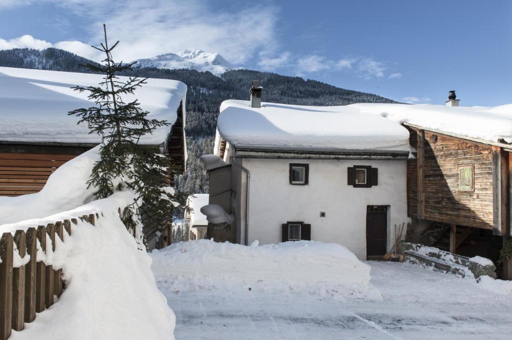 a house covered in snow next to a fence at Ferienhaus Tinizong in Tinzen