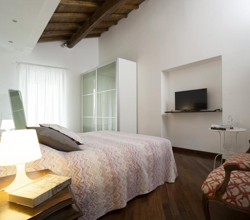 a white bedroom with a bed and a television at Alloggio La Volta in Viterbo