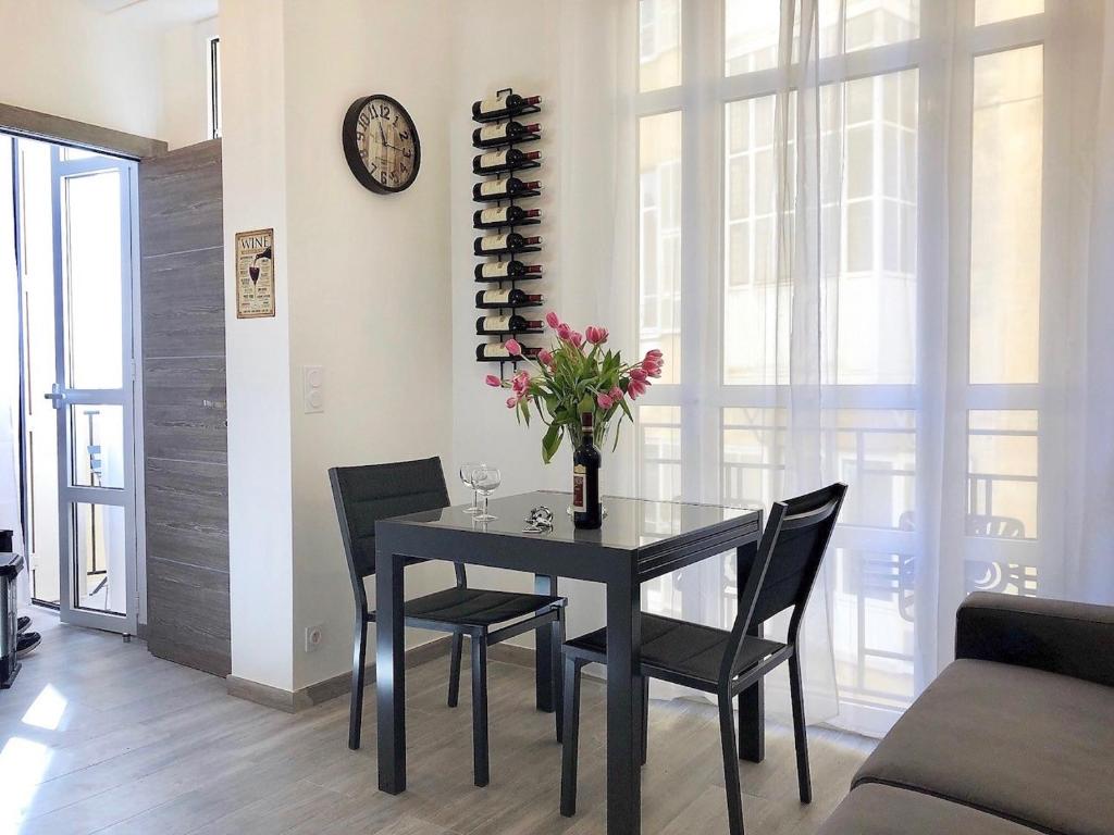 a dining room with a table and chairs and a clock at Nice Centre Flat - Modern, Quiet and Brand New in Nice
