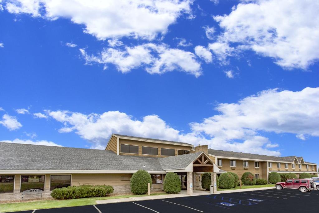 a building with a car parked in a parking lot at AmericInn by Wyndham Dickinson in Dickinson