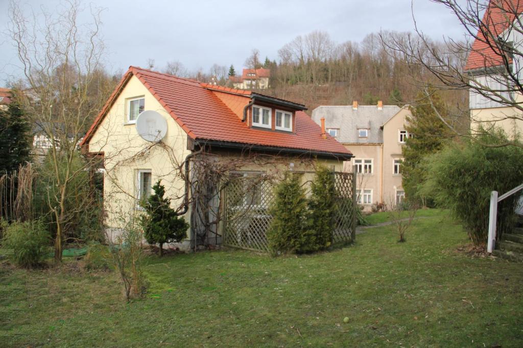 una casa con techo rojo en un patio en Ferienhaus Puttrich, en Hohnstein