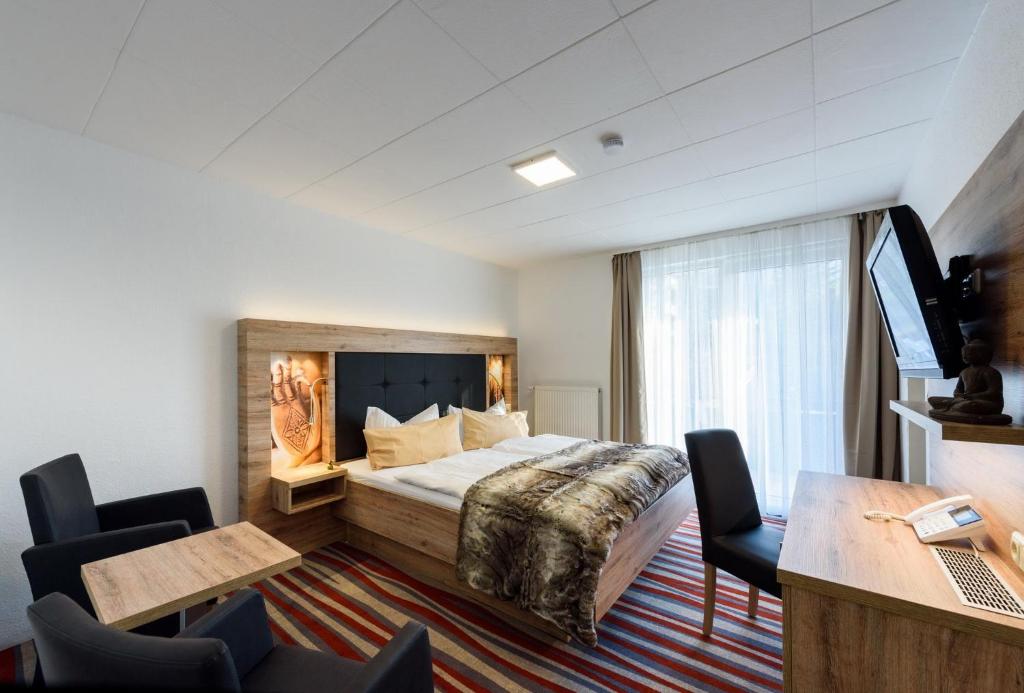 バート・ハルツブルクにあるWellness & Ayurveda Hotel Am Eichenbergのベッド、デスク、椅子が備わるホテルルームです。
