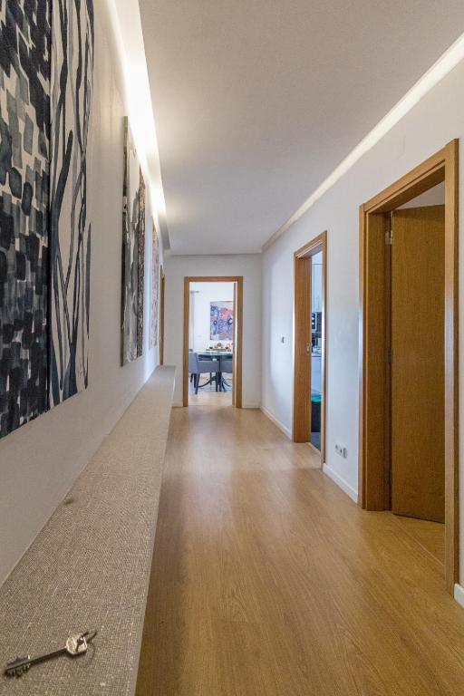a hallway with white walls and wooden floors and a table at Condomínio Ondas do Mar -Coastal Comfort- in Olhão