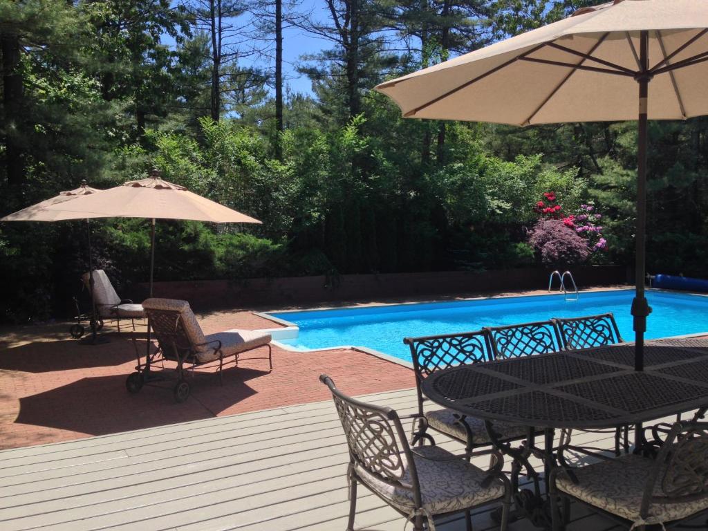 a patio with a table and umbrella and a pool at Recently Renovated, Inviting Home in Quiet Location in East Hampton