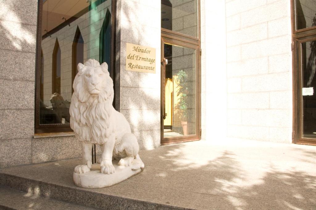 una estatua de un león sentado frente a un edificio en Mirador del Ermitage, en La Bañeza