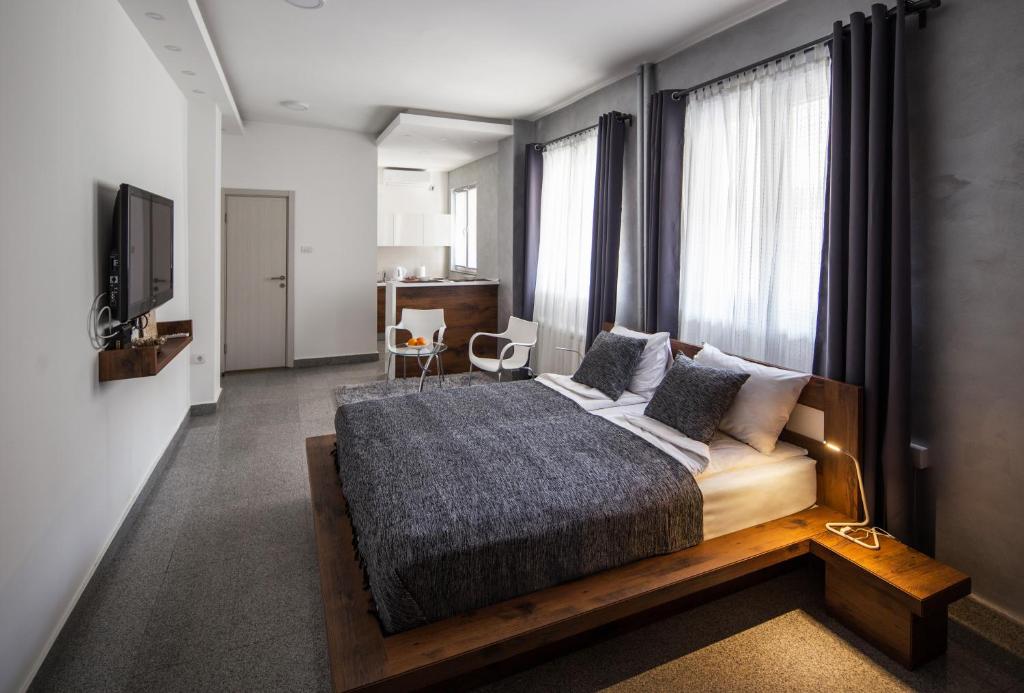 a bedroom with a bed and a tv and windows at Rose Lux in Belgrade