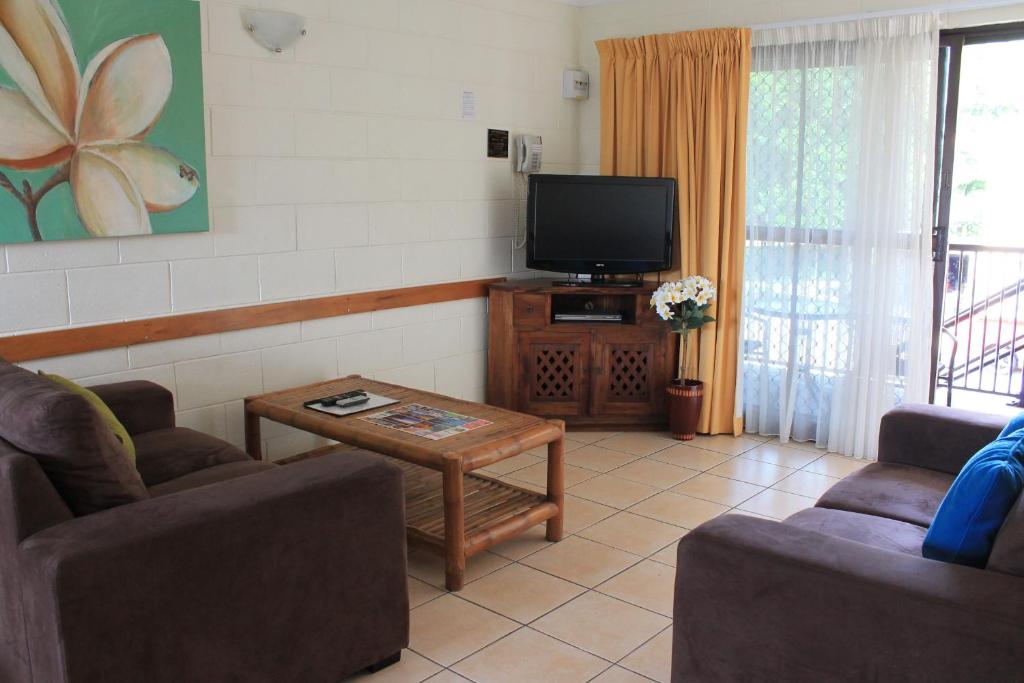 a living room with two couches and a tv at Oasis Inn Apartments in Cairns