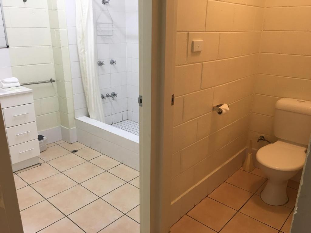 a bathroom with a toilet and a bath tub at Oasis Inn Apartments in Cairns