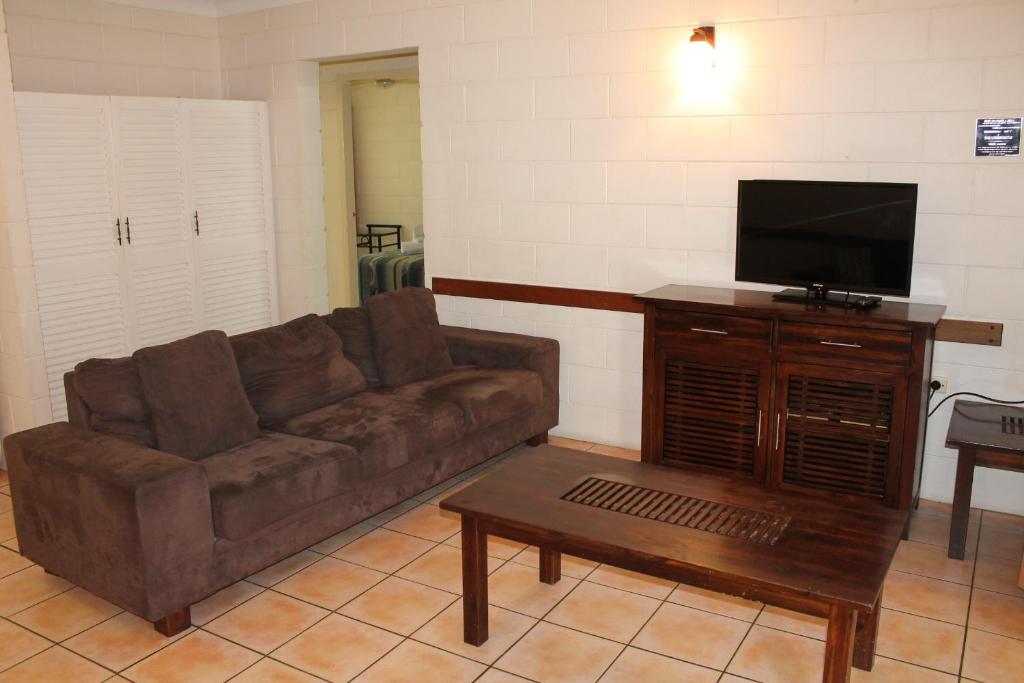 a living room with a couch and a flat screen tv at Oasis Inn Apartments in Cairns