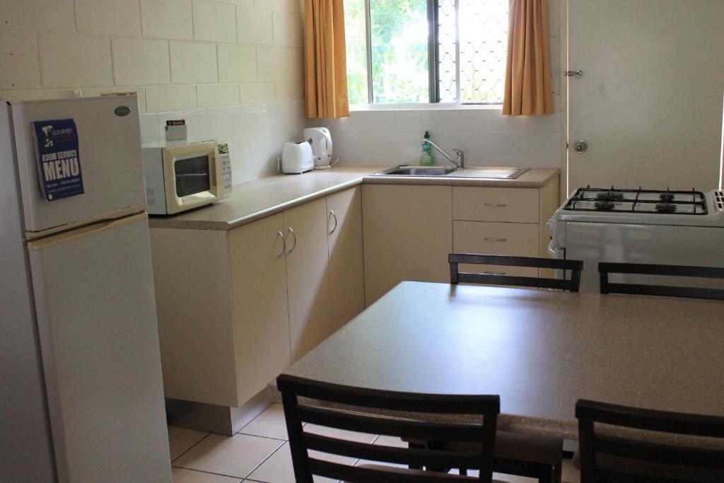 a kitchen with a table and a white refrigerator at Oasis Inn Apartments in Cairns