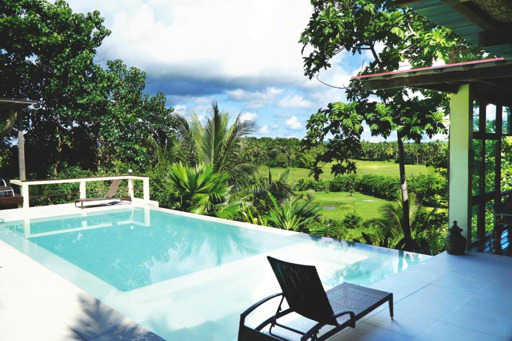 una piscina con una silla y un campo de golf en Villa Maya, en General Luna