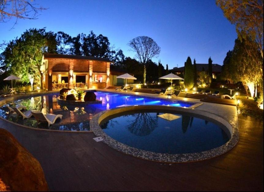 a swimming pool in front of a house at night at Leão de Judá Charme Hotel in São Sebastião do Paraíso