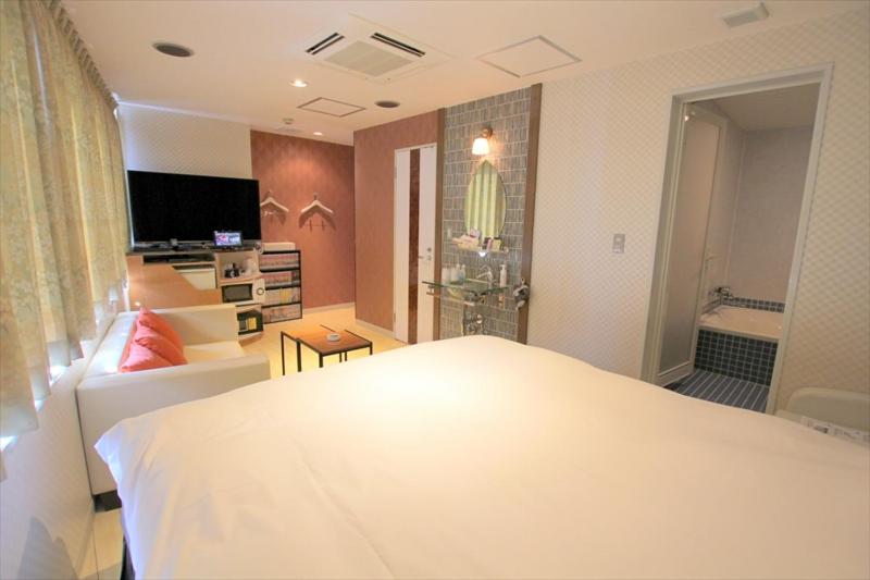 a bedroom with a white bed and a bathroom at Hotel U in Tokyo