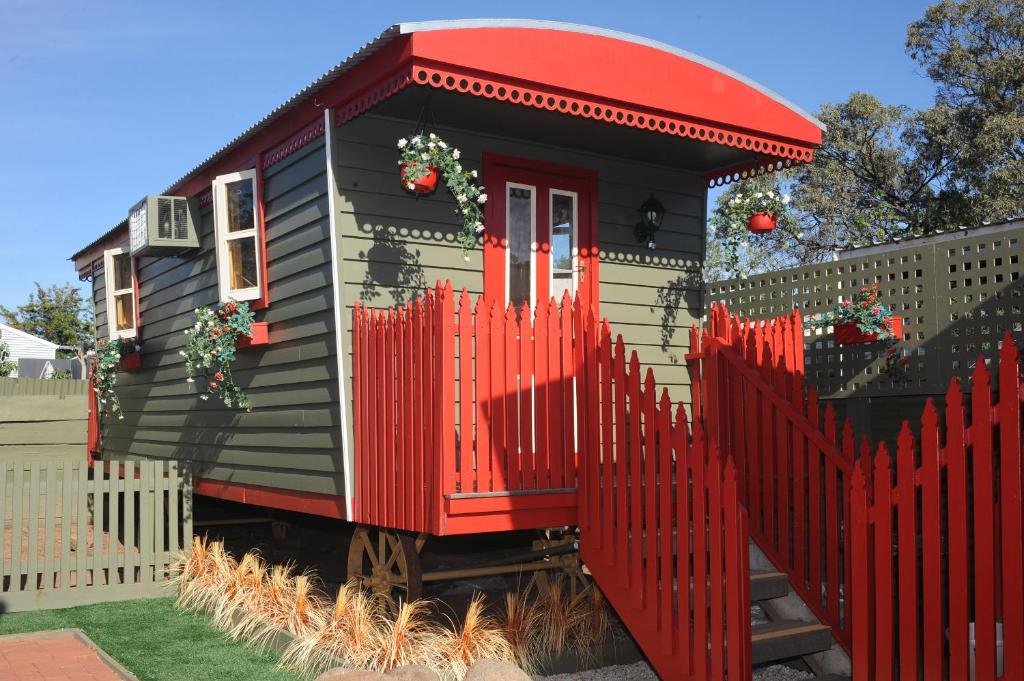 a tiny house with a red fence in a yard at Echuca Gardens in Echuca