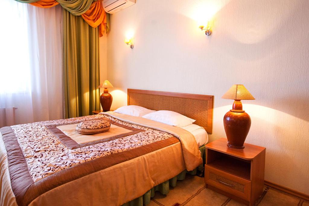 um quarto com uma cama e uma mesa com um candeeiro em Hotel Pyramida em Krasnodar
