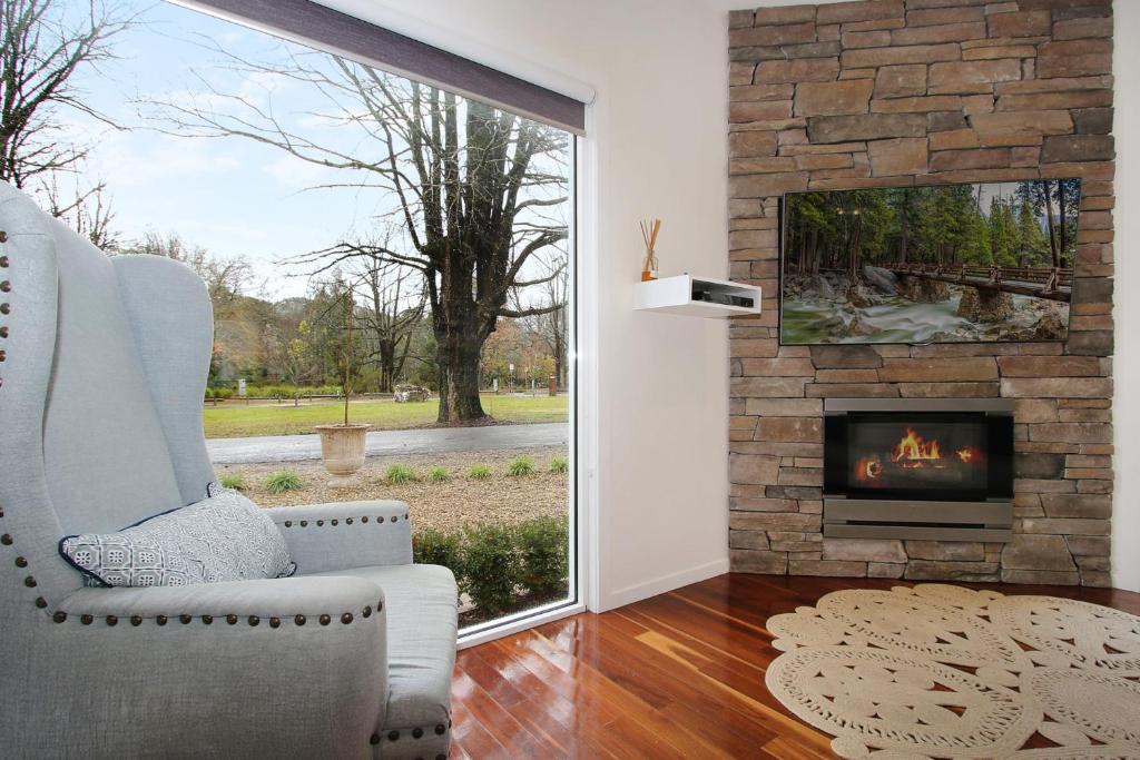 a living room with a fireplace and a chair at Beyond Bliss - Guesthouse 1 in Bright