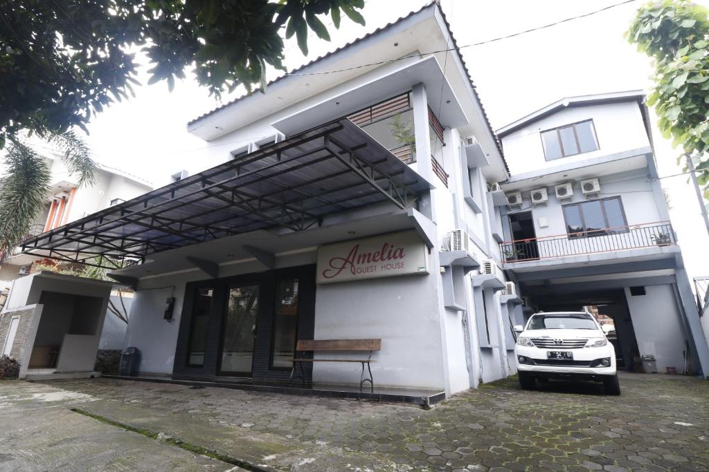 un edificio blanco con un banco delante en RedDoorz Plus near Undip Tembalang en Semarang