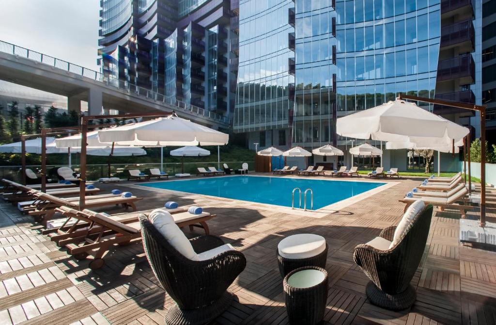 a swimming pool with chairs and tables and umbrellas at Somerset Maslak Istanbul in Istanbul