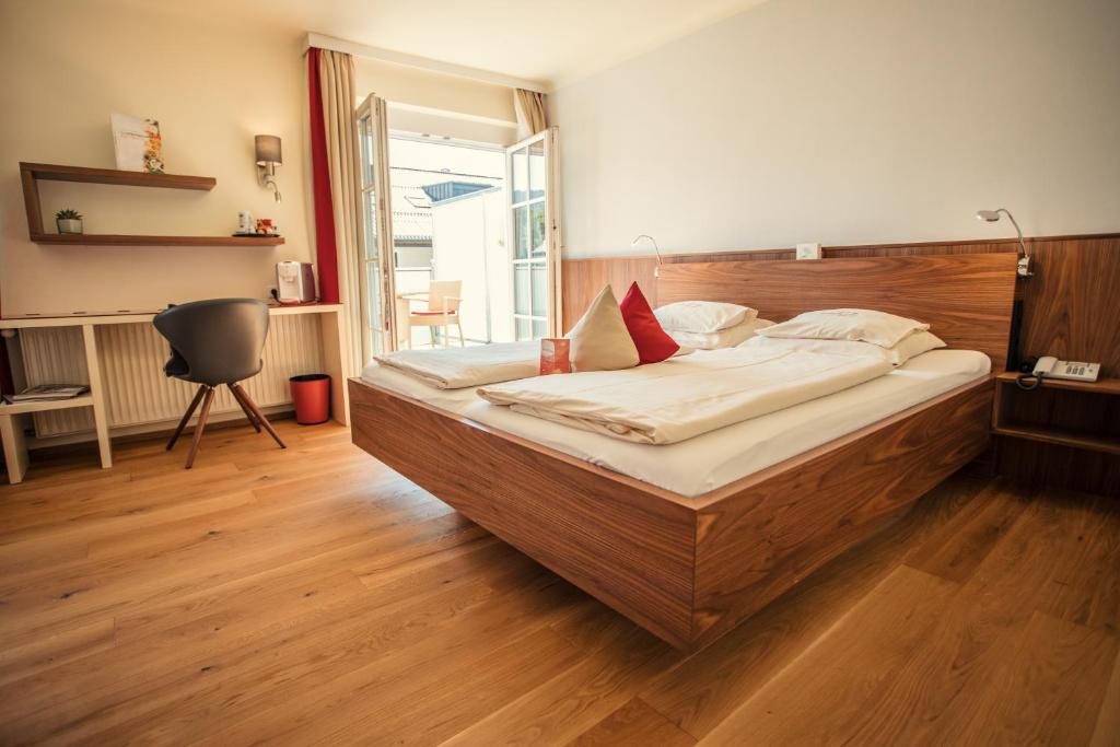 Schlafzimmer mit einem großen Bett mit einem Kopfteil aus Holz in der Unterkunft Hotel Rosenvilla in Salzburg