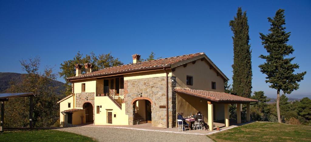 Ein Haus mit Leuten, die draußen sitzen. in der Unterkunft Bioagriturismo Poderaccio in Incisa in Valdarno