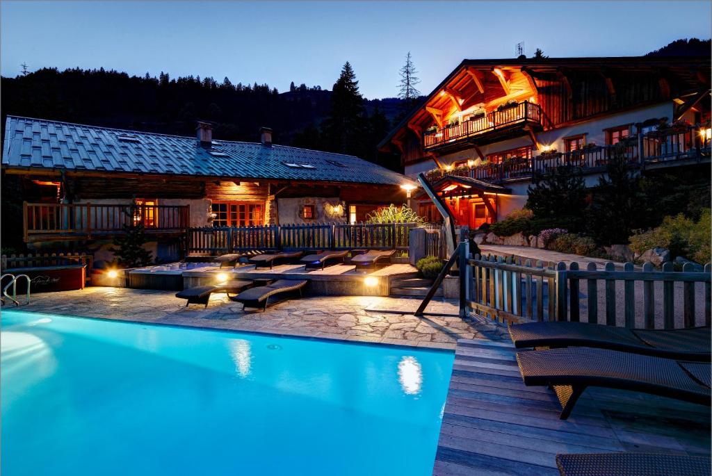 a hotel with a swimming pool in front of a building at La Ferme du Chozal, Chalet de tradition in Hauteluce