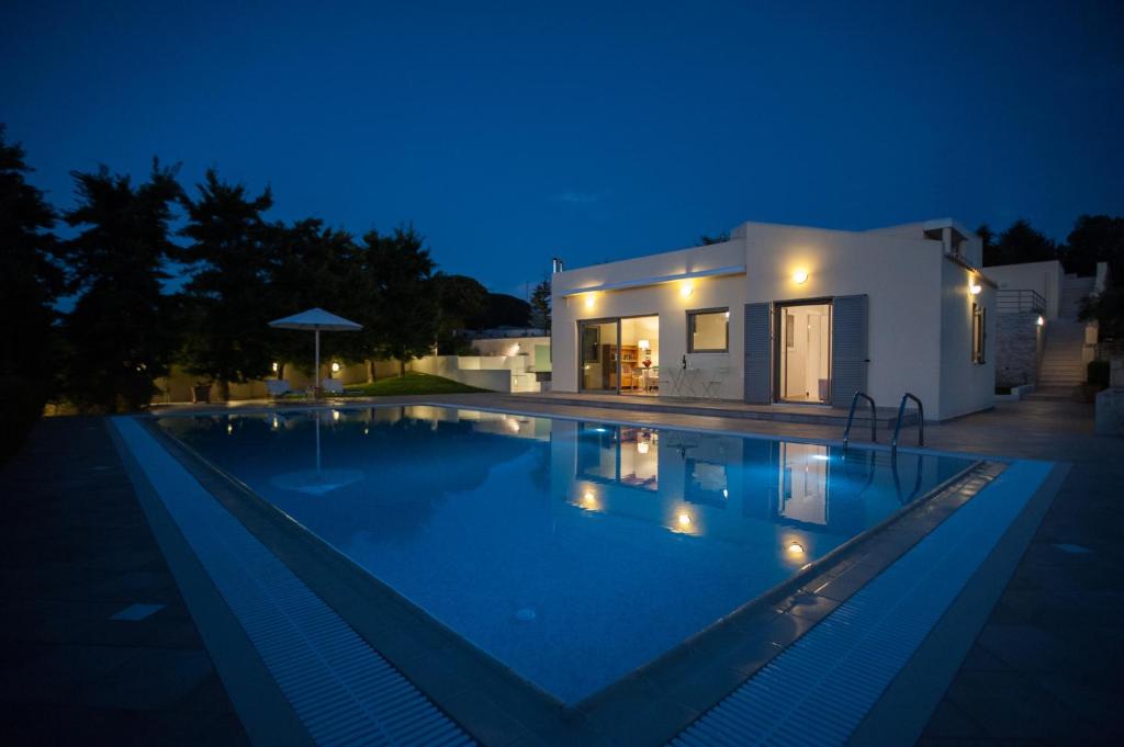 a swimming pool in front of a house at night at Aurora Elegant Residence in Episkopi (Heraklion)