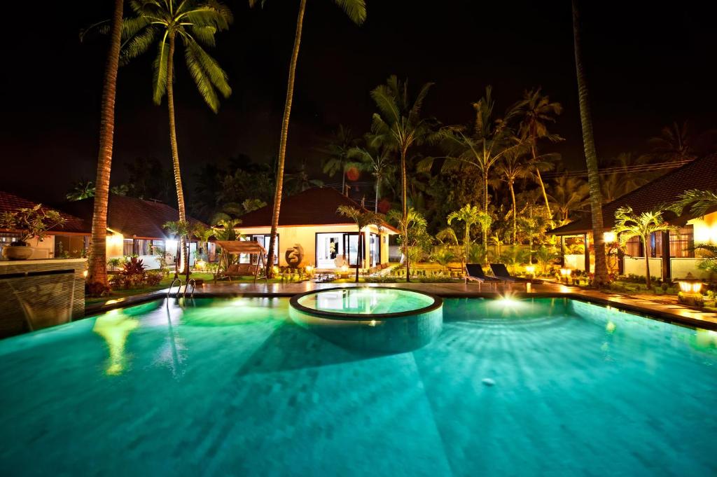 a large swimming pool at night with palm trees at Rossa Garden Hotel in Candidasa