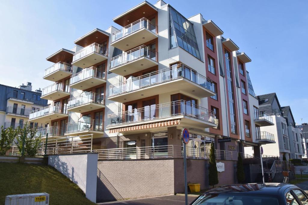 a building with balconies and a car parked in front of it at Pegaz Apartament in Świnoujście