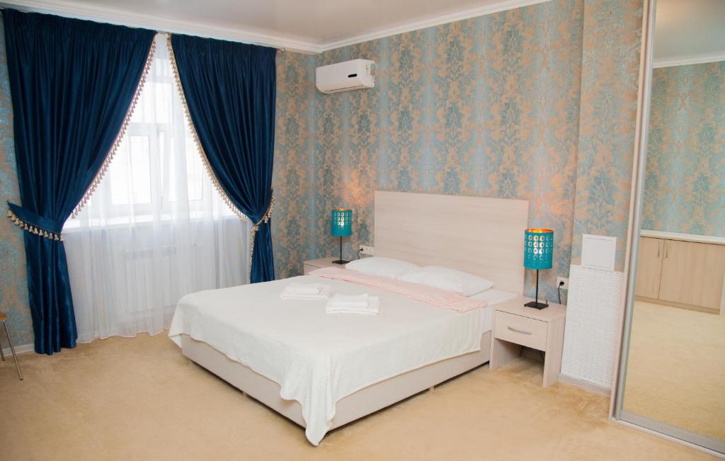 Stary Gorod Hotel في كازان: غرفة نوم بسرير ابيض وورق جدران ازرق