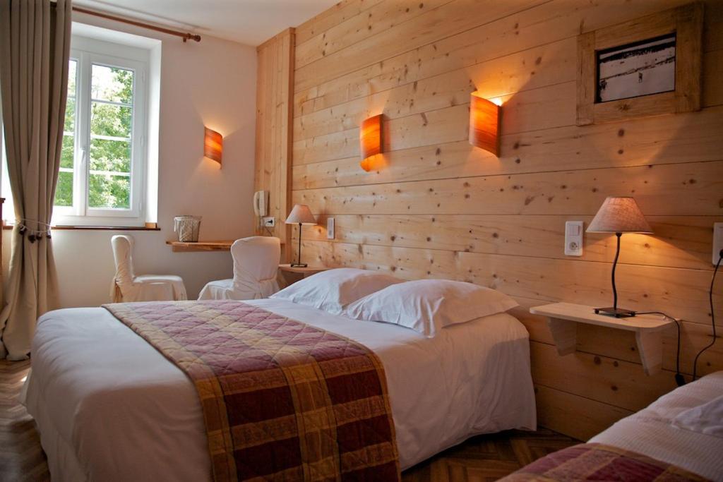 a hotel room with a bed and a wooden wall at Les Arobiers in Lamoura