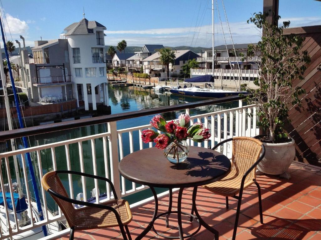 a table and chairs on a balcony with a view of the water at WATERFRONT 15 QUAY WEST in Knysna