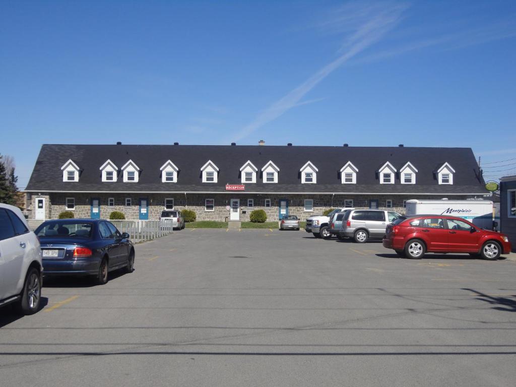 un estacionamiento con autos estacionados frente a un edificio en Motel Grande Ile, en Salaberry-de-Valleyfield
