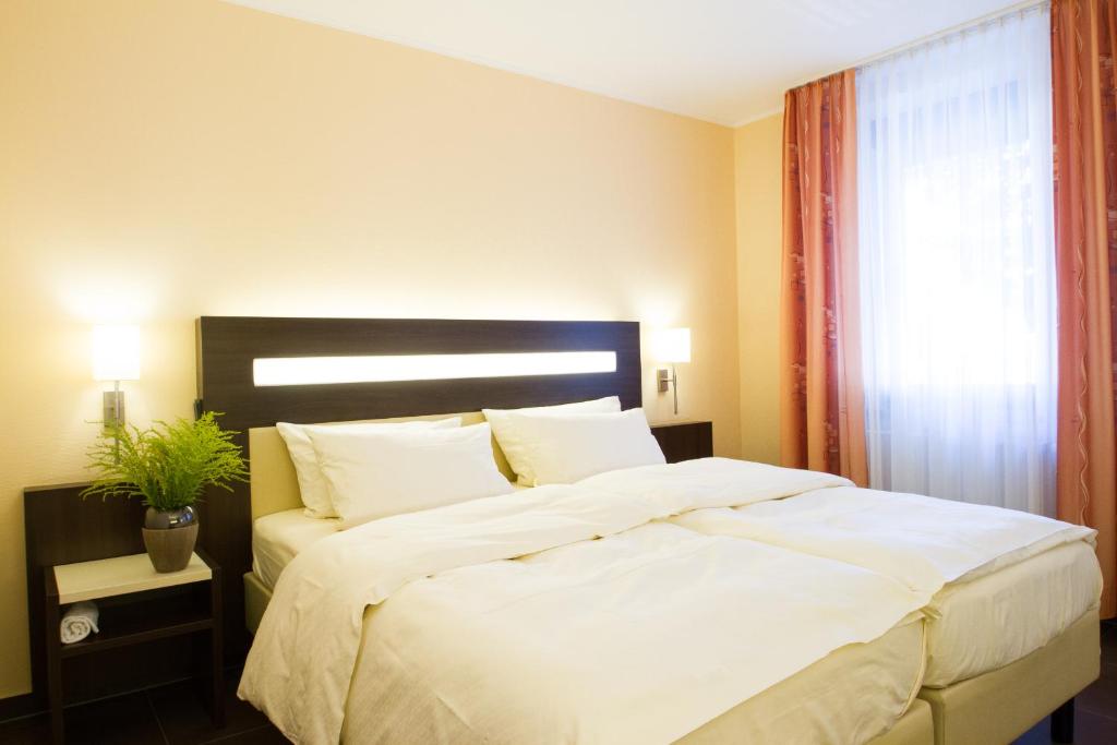 a bedroom with a large white bed with a window at SAN REMO Fine.Food.Hotel in Nuremberg