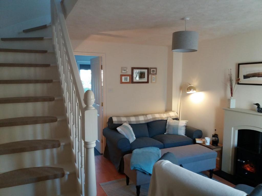 a living room with a blue couch and stairs at Hedgehope Cottage Alnwick in Alnwick