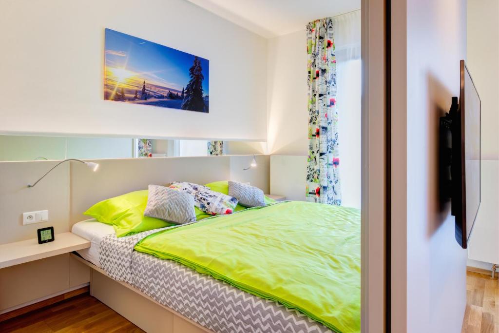 um quarto com uma cama com lençóis verdes e uma televisão em Apartman Medvědín 307 em Spindleruv Mlyn
