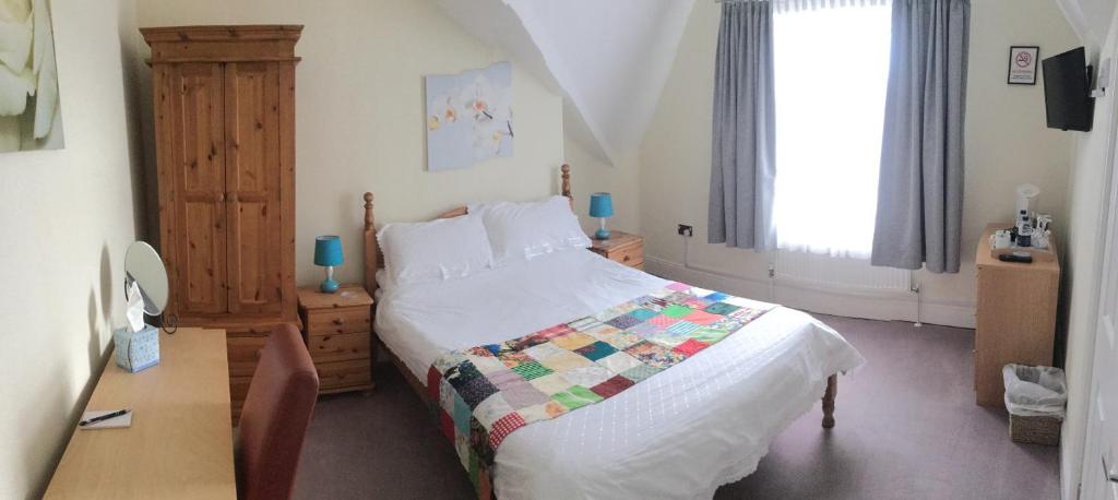 1 dormitorio con cama, escritorio y ventana en The Swallow Hotel en Bridlington