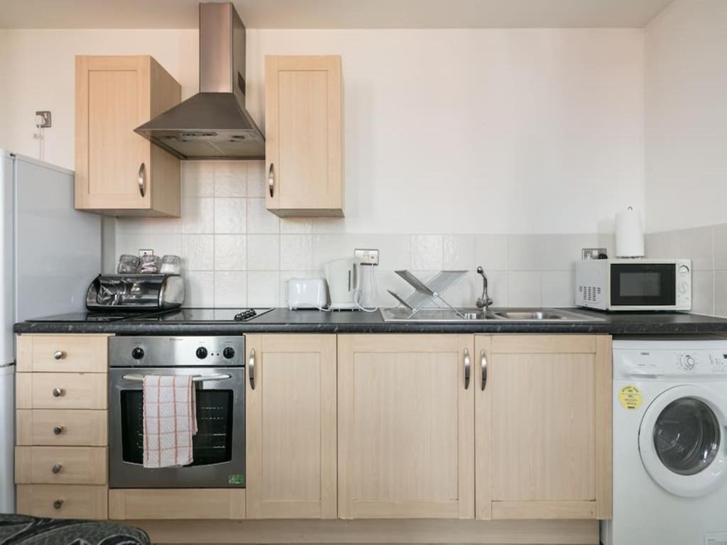 een keuken met een fornuis, een wastafel en een vaatwasser bij Deluxe 2 Bed Apartment in Manchester