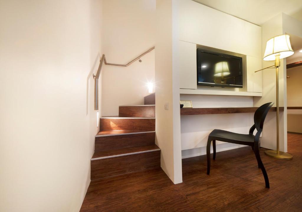 a stairway with a chair and a television on a wall at Nottingham Place Hotel in London
