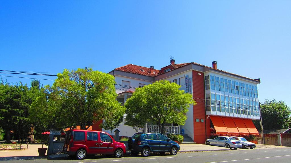 un gran edificio con coches estacionados frente a él en Hotel Os Caracoles, en Pereiro de Aguiar