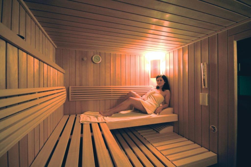 a woman is sitting in a sauna at Hotel Styrolerhof in Steeg