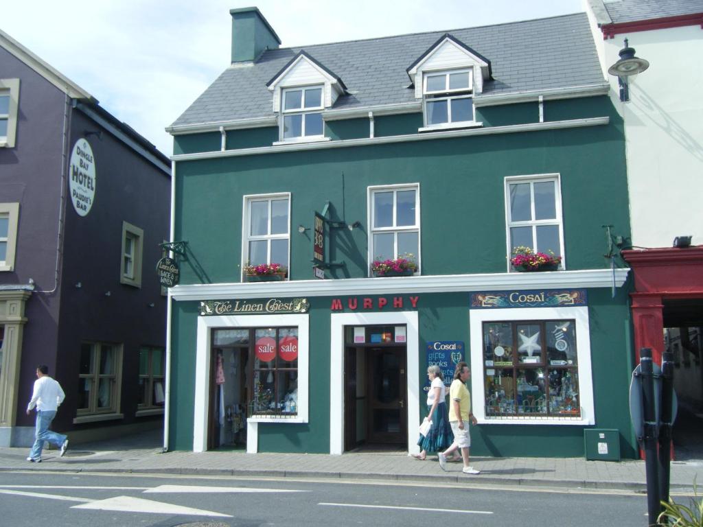 um grupo de pessoas andando em frente a um edifício verde em Murphy's Guesthouse em Dingle